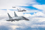 Three combat fighter jet on a military mission with weapons - rockets, bombs, weapons on wings flies high in the sky above the clouds.