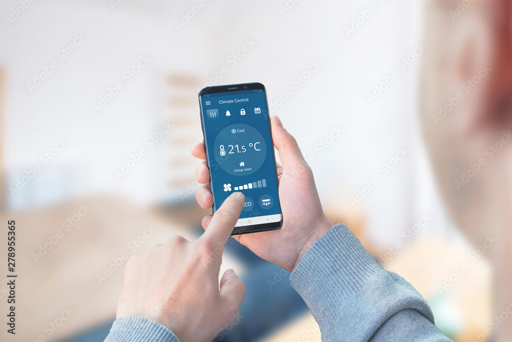 Man use the app to control the climate in the living room. Concept of a modern app with wi-fi control climate devices. - obrazy, fototapety, plakaty 