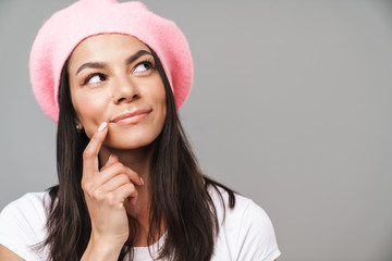 Wall Mural - Thinking dreaming young french woman in beret posing isolated over grey wall background.