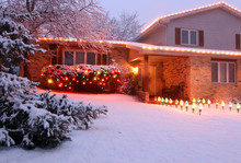 Beautiful Winter Blizzard Evening View. Front Yard Of The Private House Covered By Snow And Decorated For Winter Holiday Season Glowing In The Night. Christmas And New Year Background.