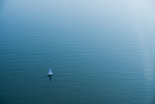 Aerial Shot Of The Beautiful Blue Ocean With A Small Boat In The Distance Sailing In The Water