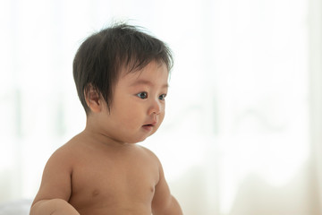 Cute Sweet Adorable Asian Baby wearing white dress Sitting on white bed smiling and playing with happiness emotional in cozy bedroom,Healthy Baby Concept