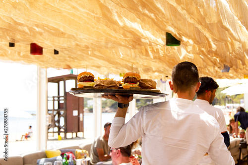 Fotografía Waiter serving burgers at a beachside restaurant
