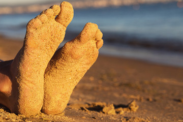 Feet on a sandy beach in the sunshine with copy space