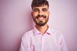 © Krakenimages.com - Young man with tattoo wearing shirt standing over isolated pink background happy face smiling with crossed arms looking at the camera. Positive person.