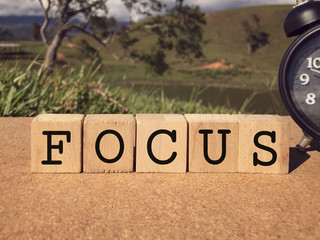 Wall Mural - Motivational and inspirational word - FOCUS written on wooden blocks. Blurred styled background.