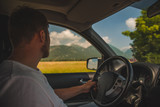 Fototapeta  - man driving car looking at mountains