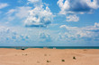 Beautiful seascape with sandy beach and clouds on blue sky in sunny day, white sun tents and umbrellas afar