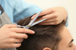 © New Africa - Barber making stylish haircut with professional scissors in beauty salon, closeup