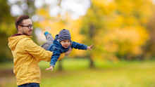 Family, Childhood And Fatherhood Concept - Happy Father And Little Son Playing And Having Fun Outdoors Over Autumn Park Background