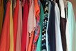 Private house closet with well organized casual clothes. Woman wardrobe with variety of bright colors tops hung on hangers.