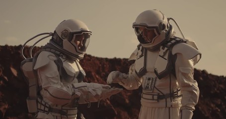 two astronauts examining sample on mars