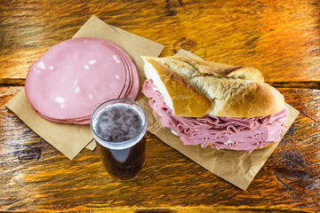 Wall Mural - Bread snack with mortadella on a rustic empress table, with typical Brazilian beer.