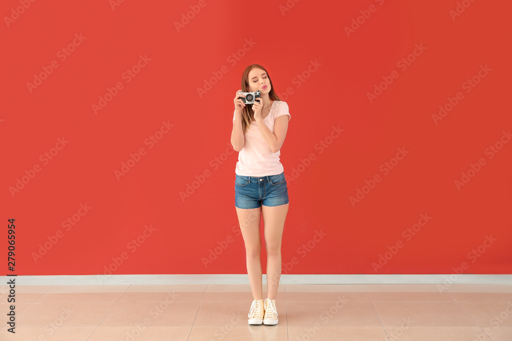 Young female photographer against color wall