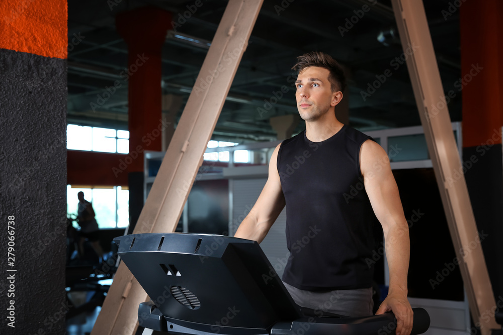 Sporty young man training on treadmill in gym
