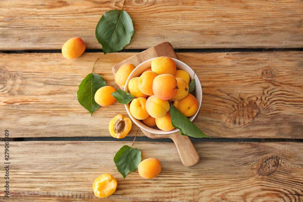 Bowl with tasty ripe apricots on wooden table