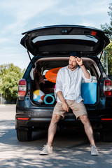 Wall Mural - handsome bearded man standing near car and touching cap