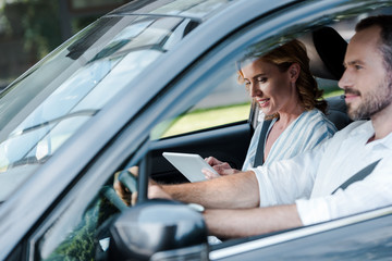 Wall Mural - selective focus of man driving car while woman holding digital tablet