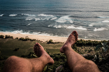 Wall Mural - pov view of legs on hill and ocean.