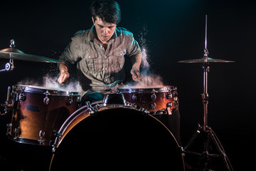 musician playing drums with splashes, black background with beautiful soft light