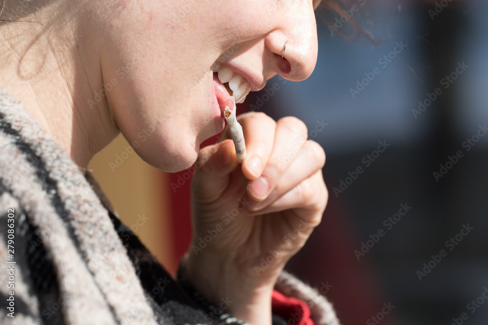 biting cigarette Foto de Stock A close up and side profile view of a woman licking the paper  of a hand rolled cigarette. Addictive habit of a stressed Caucasian lady