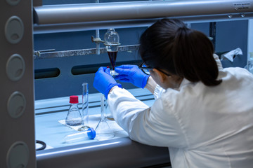 Sticker - An over the shoulder view of a female lab technician working with toxic chemicals inside a scientific research facility. Pharma and medical research.