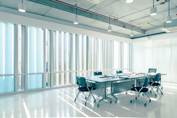 Modern Interior meeting room of marketing office with evening sunset, empty large loft style conference space with chairs and tables furniture and clean glass windows, business background