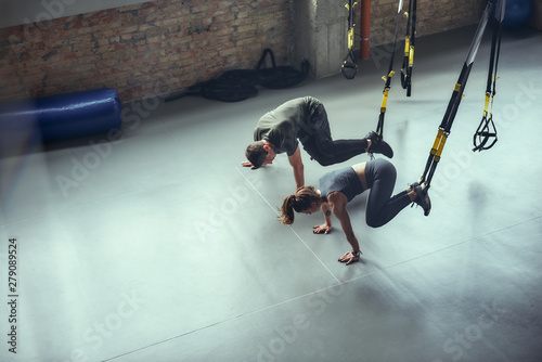 Hard Workout Man And Woman In Sportswear Doing Trx Workout At Gym