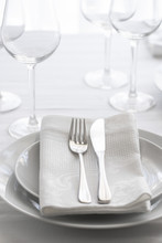 Table Setting White And Grey Colour. Empty Glasses And Plates Set With Napkin And Cutlery. Restaurant Interior Background...