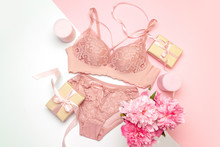 Female Lace Pink Underwear With A Pink Ribbon And Candles On A Pink Background.