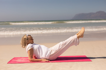 Side view of senior woman exercising at beach on a sunny day