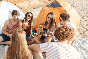 Wall Mural - Group of cheerful happy friends camping at the beach