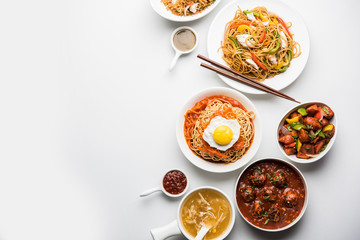 Wall Mural - Assorted Indo chinese food in group includes non vegetarian or chicken Schezwan/Szechuan hakka noodles, fried rice, manchurian, egg american chop suey, soup with spoon and chop sticks, selective focus