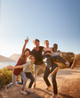 © Monkey Business - Five millennial friends on a road trip have fun posing for photos on a coastal path, full length