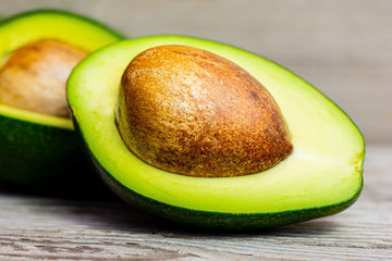 Wall Mural - Halved green avocado with stone on wooden background