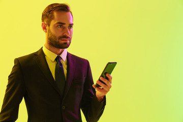 Poster - Image of serious young businessman in formal suit holding cellphone