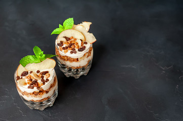  two muesli parfaits, yogurt, fresh peach, banana chips, mint, healthy breakfast on a stone background