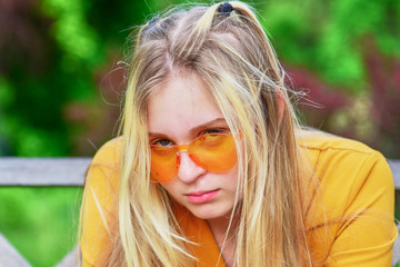 Portrait of a sad teenage girl in orange glasses.