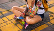 © Artem Markin - Modern girl sitting on a road marking. Carries a yellow backpack. Tattooed hands