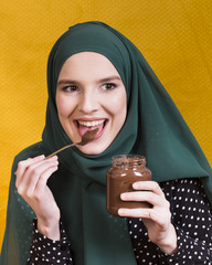 Wall Mural - Beautiful woman licking chocolate holding jar and spoon