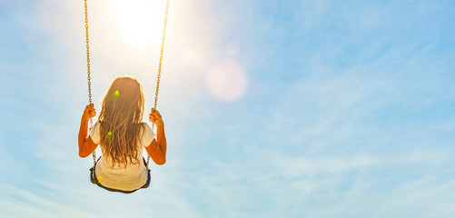 Poster - Frau auf einer Schaukel mit blauem Himmel im Gegenlicht