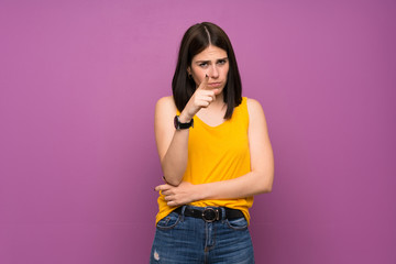 Wall Mural - Young woman over isolated purple wall frustrated and pointing to the front