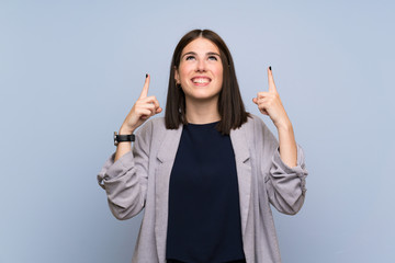 Wall Mural - Young woman over isolated blue wall pointing up a great idea