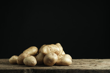 Fresh potato in silver bowl on a old oak wooden table and beautiful gray wall background.