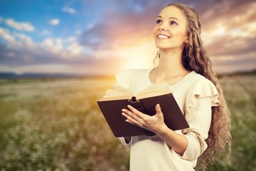 Wall Mural - Happy Woman with Bible on light background