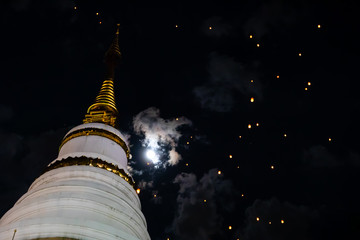 Loi Krathong and Yi Peng released paper lanterns on cloudy sky and moon and temple