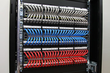 Ethernet switches connected by patch cords to patch panels in the colors of the flag of Russia. Installed in a telecommunications rack.