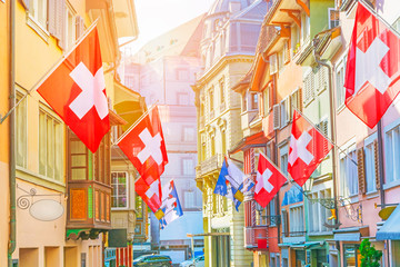 Wall Mural - Old street with old colorful buildings with bay window balconies decorated with national flags, Zurich, Switzerland