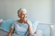 © Dragana Gordic - Happy woman relaxing on her couch at home in the sitting room. Portrait of beautiful mature woman smiling while sitting at sofa at home. Beautiful middle age woman smiling at home