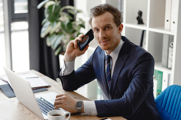 Wall Mural - Confident businessman with his smartphone and laptop